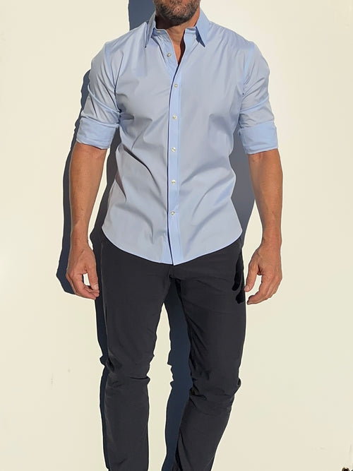 A model wearing a long-sleeved light blue dress shirt with a collar, button-up shirt.