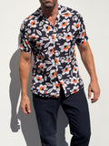 Man wearing a black floral patterned shirt against a white background