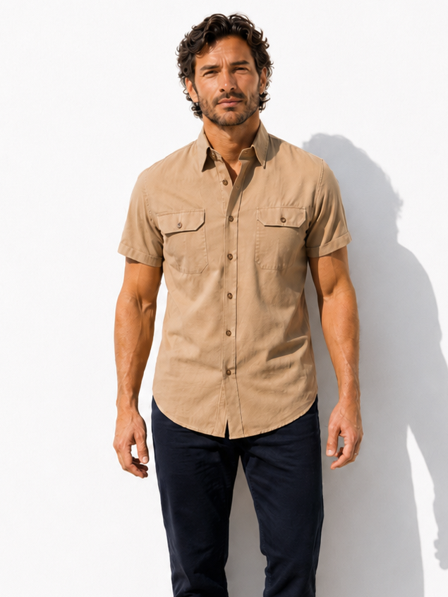 Man wearing a beige short-sleeve shirt and dark pants against a white background